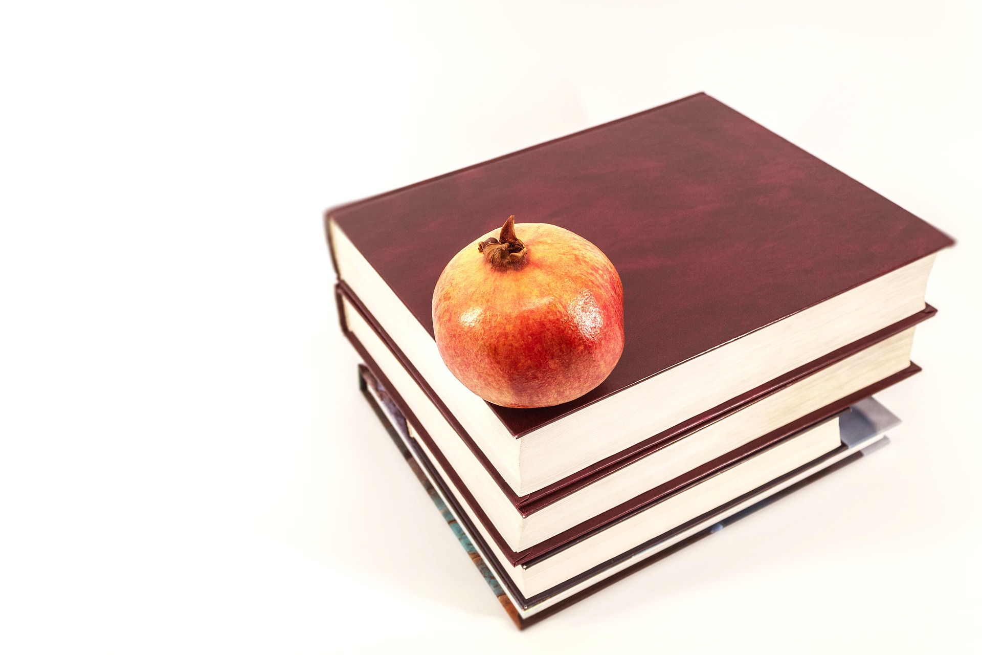 livros para estudo em cima de uma mesa com uma maçã em cima deles
